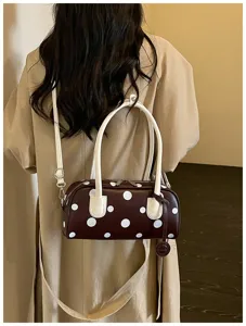 Detailansicht der braunen Pünktchen-Bowlingtasche mit weißen Griffen und Schultergurt.