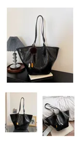 Black patent leather tote bag detail shot, featuring plush pom-pom and beaded pendant.