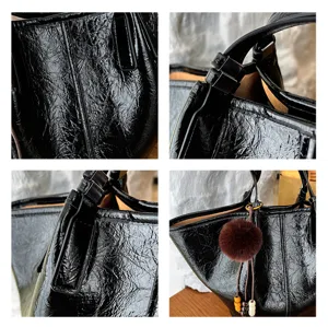 Black crinkled leather handbag detail shot showing texture, strap, and cute pom-pom charm.