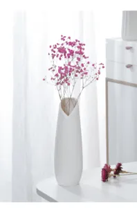 Minimalist white ceramic vase detail with delicate pink dried flowers for home decor and table setup.