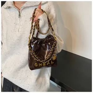 Dettaglio borsa a catena trapuntata marrone scuro, mini borsa hobo di lusso con tracolla.