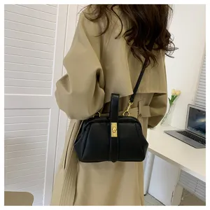 Vista dettagliata della borsa a mano nera in pelle con dettagli dorati abbinata al trench beige.