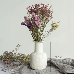 Détail du vase en céramique blanche avec fleurs séchées pour décoration d'intérieur élégante.
