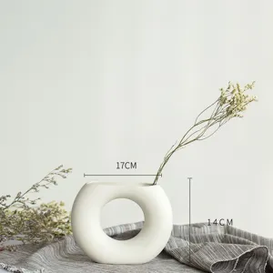 Vue détaillée du vase en céramique nordique blanche style donut avec dimensions 17x14cm et fleurs.