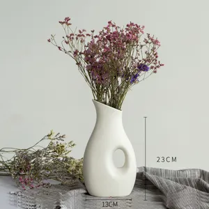Vase en céramique blanche nordique en gros plan avec des fleurs séchées pour belle décoration.