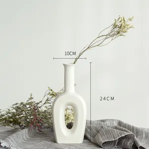 Vue détaillée d'un vase en céramique blanche creuse minimaliste avec des fleurs séchées