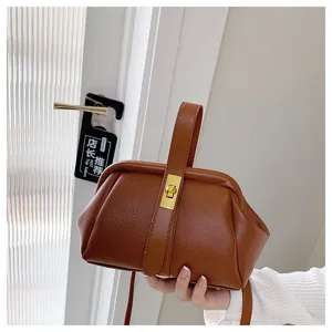 Dettaglio borsa marrone in pelle martellata con chiusura metallica e manico elegante.