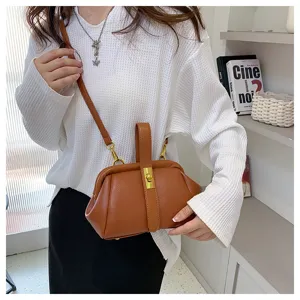 Vista dettagliata della borsa a tracolla marrone con motivo litchi indossata dal modello con stile.