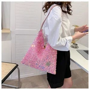 Close-up view of a sparkling pink sequin shoulder hobo bag worn by a model in an indoor setting.