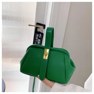 Borsa verde con texture litchi e chiusura a scatto, dettaglio di pelle e metallo dorato.