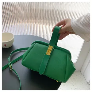 Dettaglio della borsa a mano in pelle verde con trama litchi e chiusura metallica dorata.