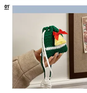Christmas crochet cross body bag detail, green knitted pouch with red bow and yellow bell.