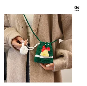 Christmas crochet crossbody bag for kids, green knit purse with bell detail and drawstring design.