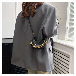 Schwarze Lackleder Crescent Mini Umhängetasche mit auffälliger goldener Kettendetail.
