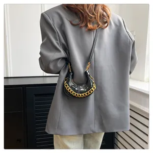 Schwarze Mini-Crescent-Umhängetasche aus Wachsleder mit auffälliger goldener Kette.