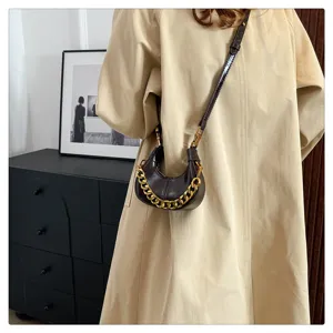 Nahaufnahme der stilvollen dunkelbraunen Mini-Schultertasche aus Leder mit Goldkette.