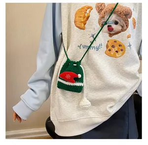 Detailed view of a cute green Christmas crochet cross-body bag with Santa hat decoration.