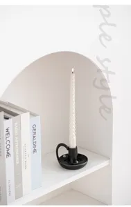 Vue détaillée d'un bougeoir en céramique noire de style nordique avec une bougie torsadée.