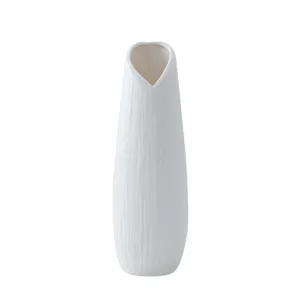 White minimalist ceramic vase with vertical ribbed texture and unique V-shaped opening design.