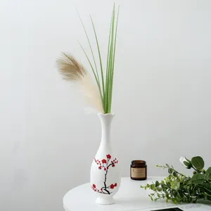 Vase en céramique blanche avec fleurs de prunier rouges peintes, décoration d'intérieur.