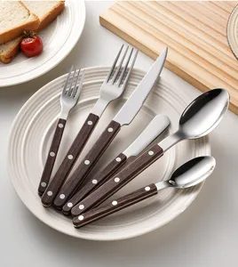 Stainless steel cutlery set detail view with elegant wood grain handle design for dining table.