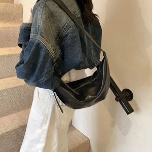 Vue détaillée d'un sac hobo élégant en cuir noir porté en bandoulière par le mannequin.