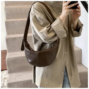 Sac croissant marron sous les aisselles en détail, design minimaliste et sangle réglable.