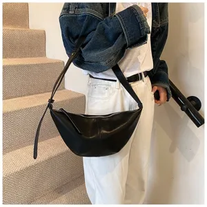 Vue détaillée du sac porté épaule minimaliste noir en croissant sur les escaliers.