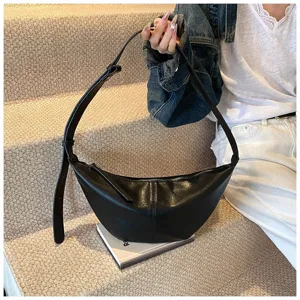 Vue détaillée du sac sous-bras en cuir noir, montrant une texture souple et une forme élégante.