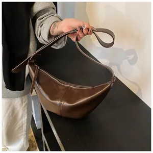 Détail de sac hobo en cuir marron, sac bandoulière rétro style boulette pour femme automne.