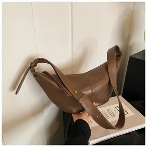 Gros plan du sac hobo en cuir marron avec une texture fine et une fermeture éclair lisse.