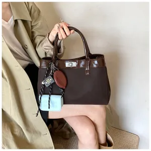 Detail view of stylish brown women handbag with metal lock and cute charm pendants for daily look.