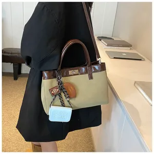Canvas leather handbag detail view, featuring turn-lock closure and cute charms.