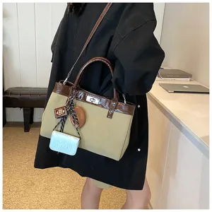 Detailed closeup of autumn color-blocked tote handbag with turn-lock and charms.