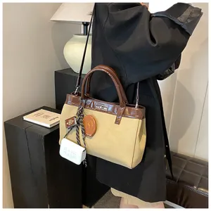 Chic canvas crossbody bag for women, with contrast color design and cute hanging accessories.