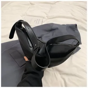Gros plan détaillé du sac à aisselles dumpling en cuir PU noir élégant avec bandoulière réglable.