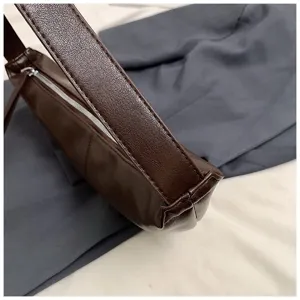 Détail de sac sous les bras en cuir synthétique marron foncé, vue rapprochée rétro.