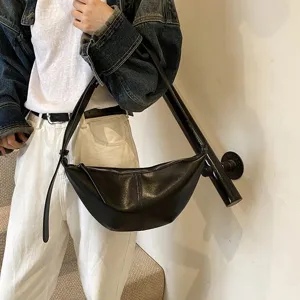 Vue détaillée du sac croissant en cuir noir sous les bras, avec fermeture éclair.