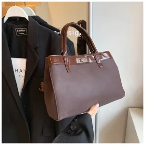 Close-up detail of stylish brown suede handbag with glossy contrast trim and metal twist lock.