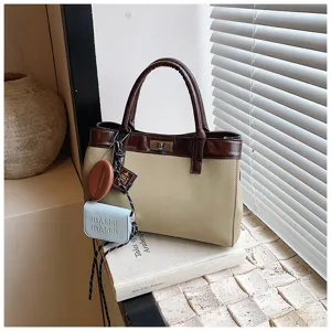 Detailed view of casual two-tone handbag featuring brown leather trim and cute hanging charms.