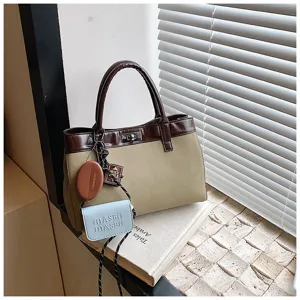 Stylish women's minimalist handbag with contrasting brown trim and chic hanging accessories.