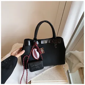 Detailed view of a chic black handbag with glossy trim, metal turn-lock and trendy pendants.