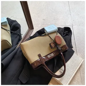 Detail shot of a stylish two-tone handbag with glossy brown and khaki fabric, metal lock.