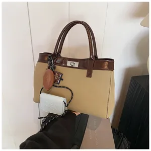 Close-up view of brown khaki tote handbag with twist lock, white pouch, and dual top handles.
