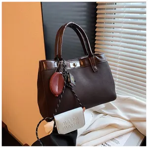 Detailed view of the stylish brown women handbag with chic pendants and metal lock closure.