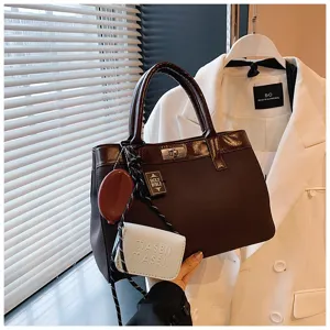 Detailed view of stylish brown handbag with chic pendant accessories and lock design.