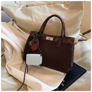 Detail view of women brown tote handbag with turn lock closure and chic hanging pouch accessory