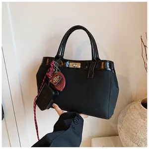 Detail view of a stylish black handbag featuring a gold-tone lock and decorative mini pendants.