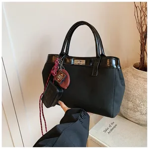 Detailed shot of stylish black top handle bag with chic charms and shiny trim design.