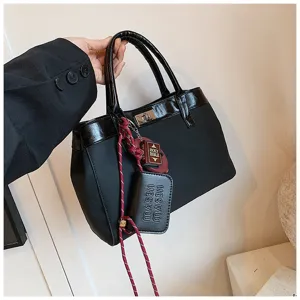Close-up detail of black fashion women handbag, patent leather trim and cute hanging pendants.